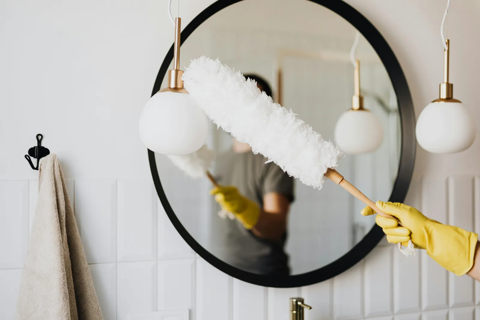 Professional cleaning service - person in yellow gloves cleaning mirror
